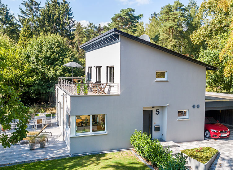 Hausbau-Beispiel Meisterstück-HAUS, Pultdach Haus mit Dachterrasse und angebauter Garage in grüner Umgebung, Hausbau mit Frau Fertighaus