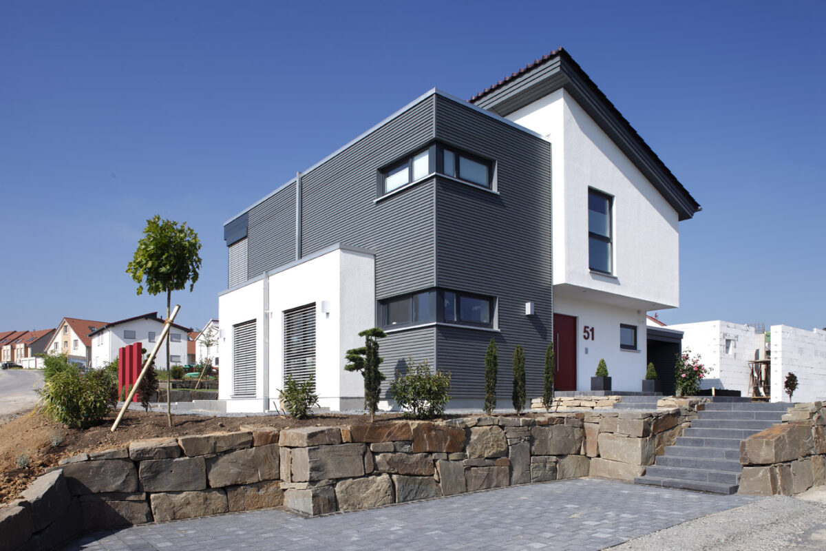 Bild zeigt ein modernes, architektonisch variantenreiches Haus mit Pultdach und Flachdach-Anbau von Meisterstück-Haus. Blog Frau Fertighaus